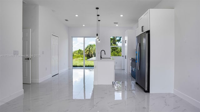 kitchen featuring white cabinets, an island with sink, decorative light fixtures, freestanding refrigerator, and marble finish floor