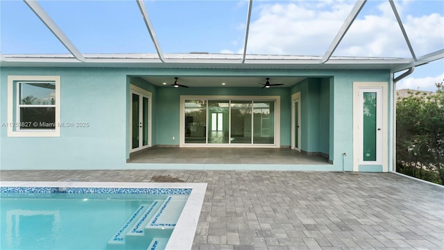 back of house featuring metal roof, a standing seam roof, a lanai, and stucco siding