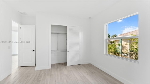 unfurnished bedroom featuring a closet, baseboards, visible vents, and light wood finished floors