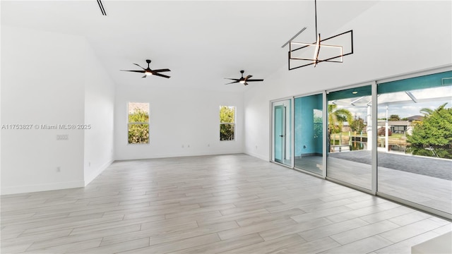 unfurnished room with light wood-style floors, high vaulted ceiling, baseboards, and a ceiling fan