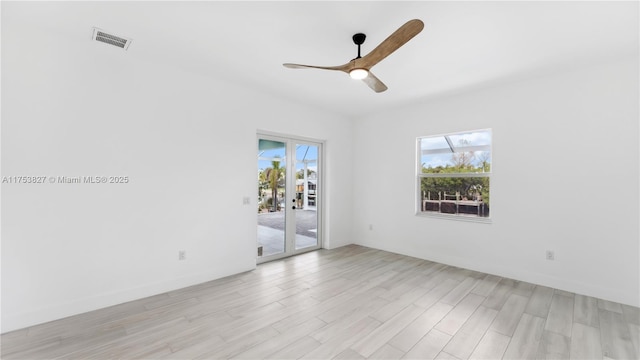 spare room featuring light wood-type flooring, visible vents, and a ceiling fan