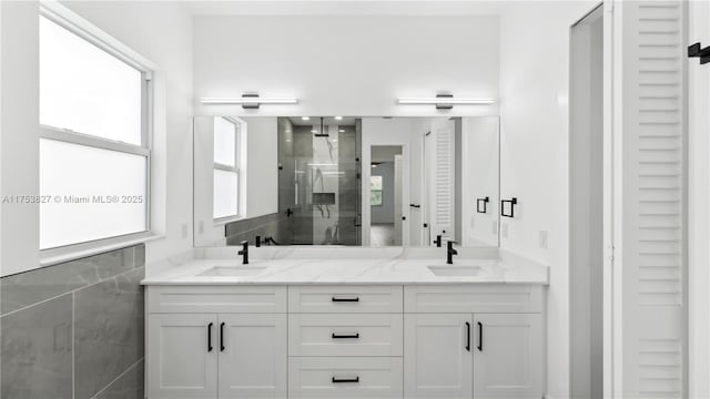 bathroom with double vanity, a shower stall, tile walls, and a sink