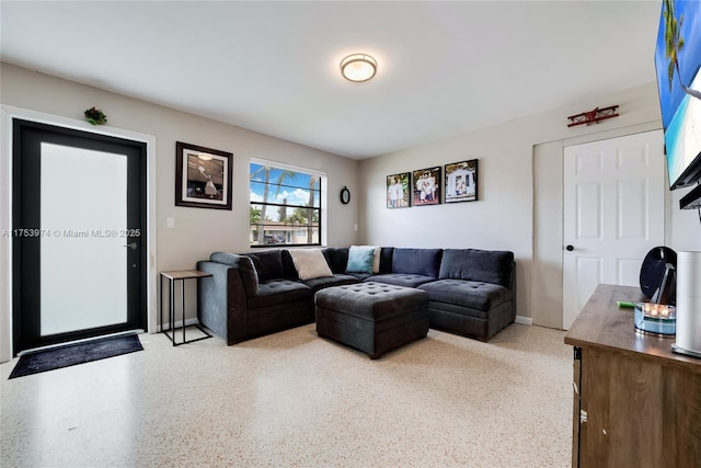 living area featuring light speckled floor and baseboards