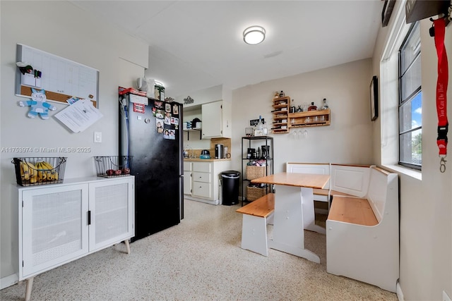 kitchen featuring light speckled floor, white cabinetry, light countertops, freestanding refrigerator, and open shelves