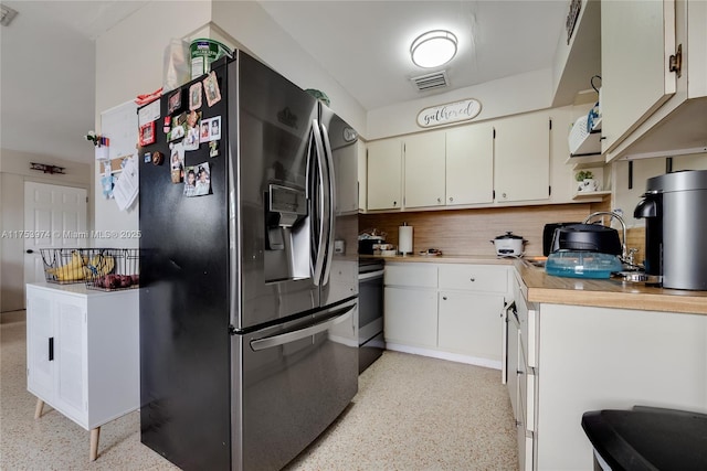 kitchen featuring visible vents, stainless steel fridge with ice dispenser, light countertops, light speckled floor, and backsplash