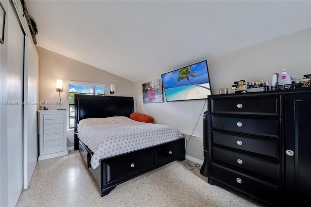 bedroom featuring light speckled floor, lofted ceiling, and baseboards