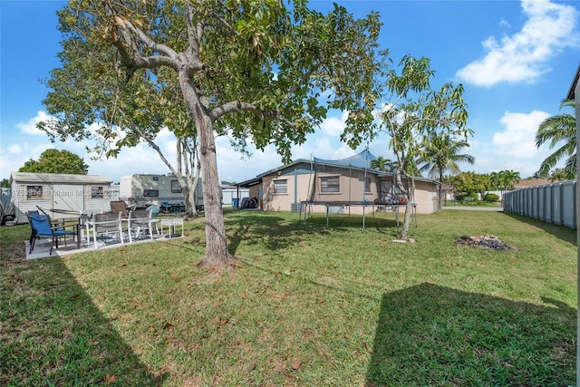 view of yard with an outbuilding, a patio, fence, a storage unit, and a trampoline