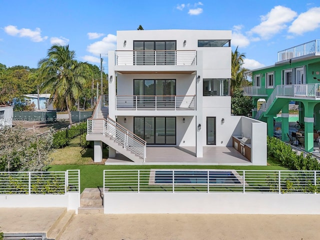 back of property with stucco siding, a patio, stairway, and a balcony