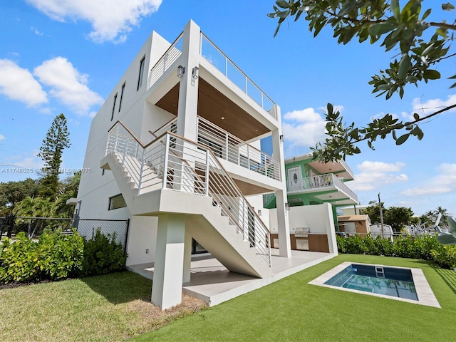 rear view of property with stairs, stucco siding, a patio, and an outdoor kitchen