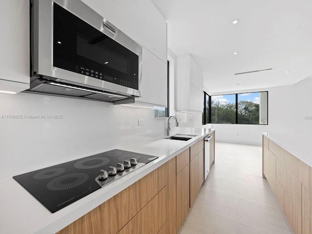 kitchen with stainless steel appliances, modern cabinets, light countertops, light brown cabinets, and recessed lighting
