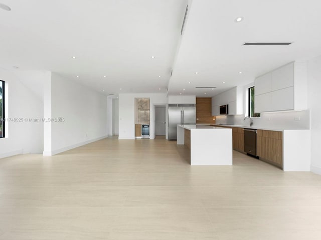 kitchen with stainless steel appliances, modern cabinets, open floor plan, a kitchen island, and recessed lighting