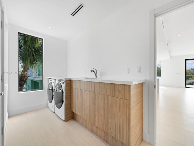 washroom with washing machine and clothes dryer, cabinet space, and recessed lighting