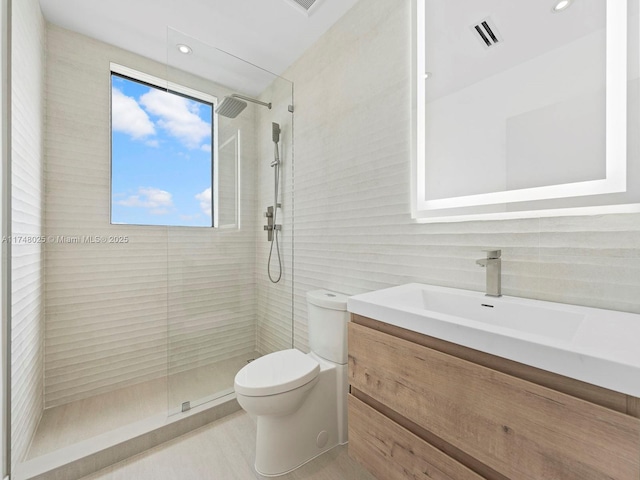 bathroom with tile walls, a tile shower, vanity, and recessed lighting