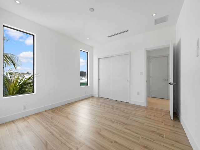 unfurnished bedroom with light wood finished floors, recessed lighting, and a closet