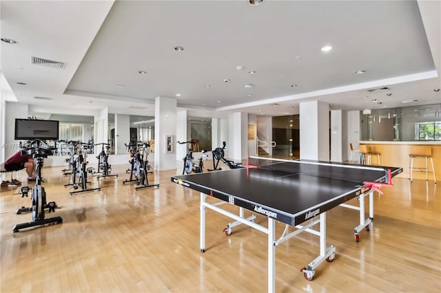 recreation room featuring visible vents, wood finished floors, and a raised ceiling