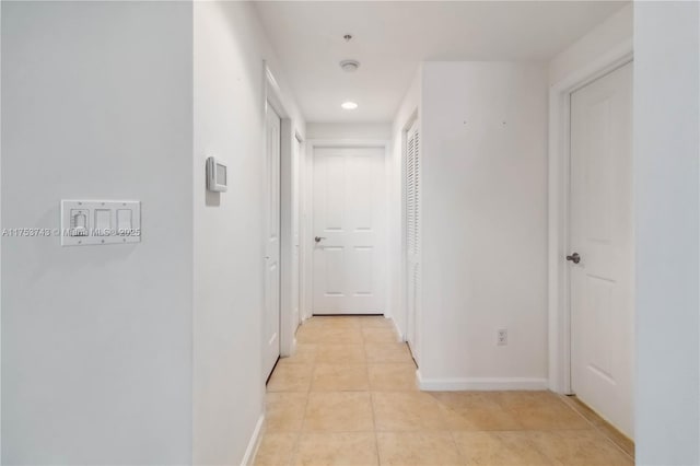 corridor featuring light tile patterned floors, baseboards, and recessed lighting