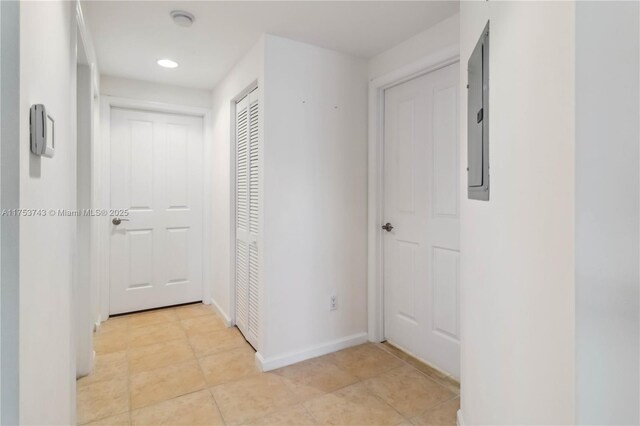 corridor featuring electric panel, recessed lighting, baseboards, and light tile patterned flooring