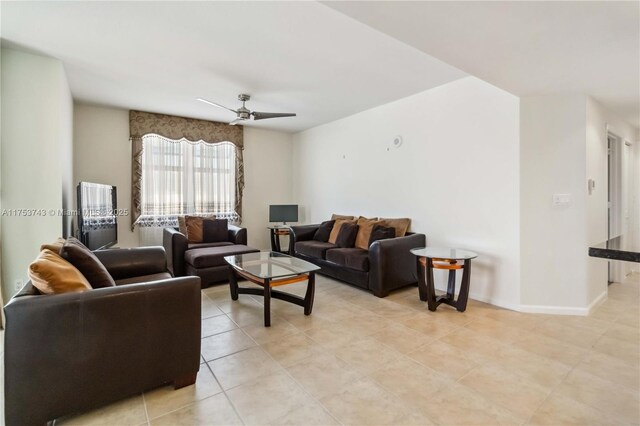 living area with light tile patterned floors, baseboards, and ceiling fan