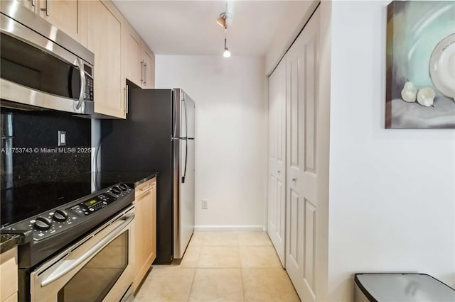kitchen featuring track lighting, light tile patterned flooring, stainless steel appliances, light brown cabinets, and baseboards