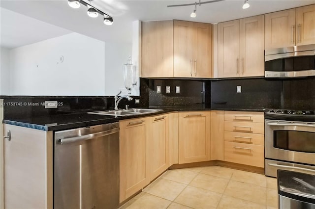 kitchen featuring rail lighting, appliances with stainless steel finishes, a sink, decorative backsplash, and light brown cabinets