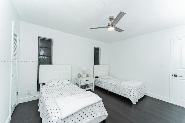 bedroom with dark wood-type flooring, a ceiling fan, and baseboards