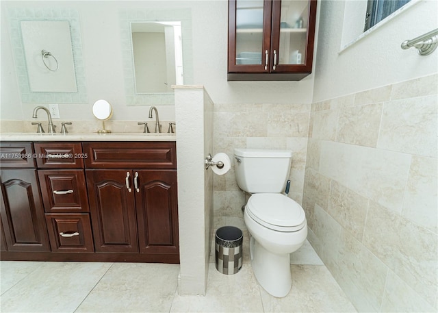 bathroom with toilet, tile walls, a sink, and tile patterned floors