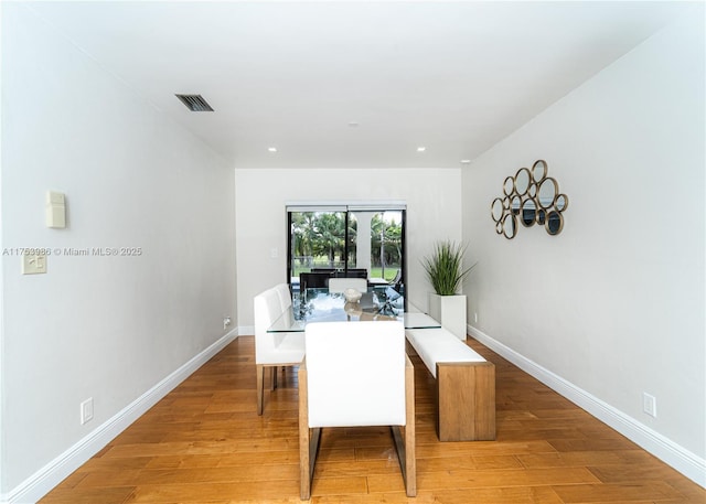 dining room with light wood finished floors, visible vents, and baseboards