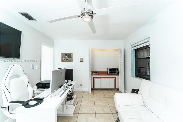 office space featuring light tile patterned floors, baseboards, visible vents, and a ceiling fan