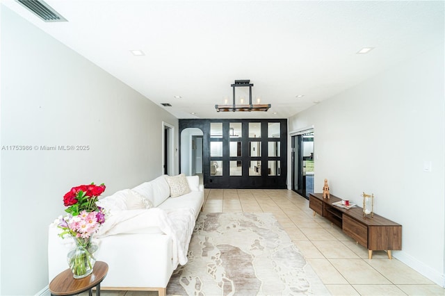 living room with arched walkways, french doors, light tile patterned flooring, and visible vents