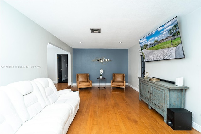 living room with baseboards, visible vents, and wood finished floors