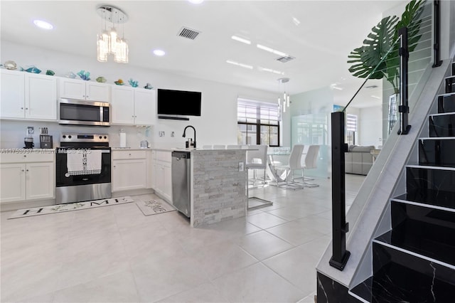 kitchen featuring a peninsula, visible vents, appliances with stainless steel finishes, and white cabinets