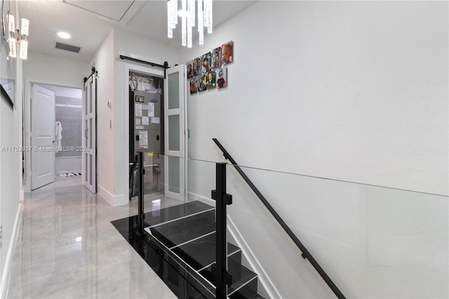 staircase featuring a barn door, visible vents, and baseboards