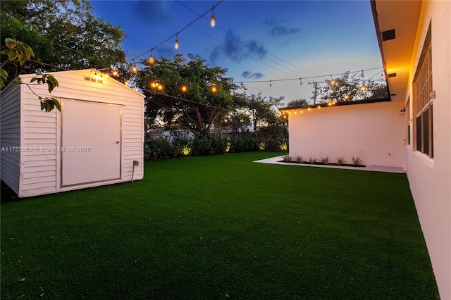 view of yard with fence, a storage unit, and an outbuilding