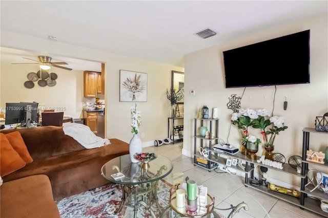 living area with light tile patterned floors, baseboards, visible vents, and a ceiling fan