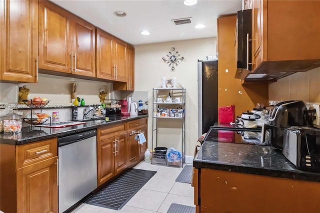 kitchen with brown cabinets, visible vents, appliances with stainless steel finishes, light tile patterned flooring, and a sink