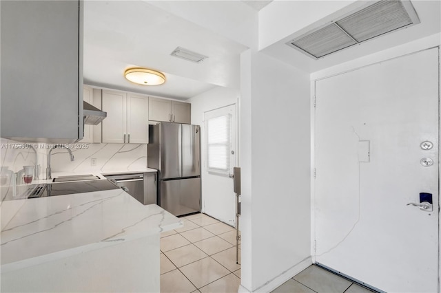 kitchen featuring light tile patterned floors, stainless steel appliances, visible vents, light stone countertops, and extractor fan