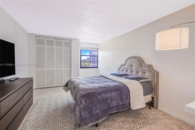 bedroom with a closet, a textured ceiling, and baseboards