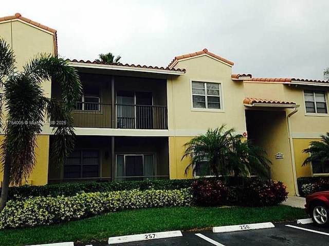 view of front of home with uncovered parking, a tile roof, and stucco siding