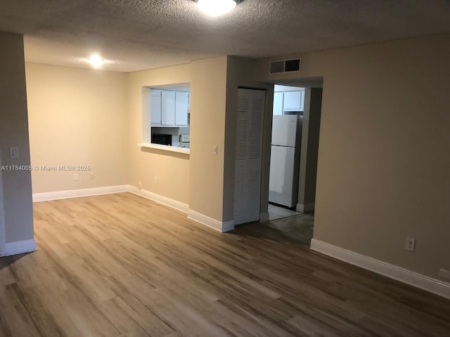 empty room featuring baseboards, a textured ceiling, visible vents, and dark wood-style flooring