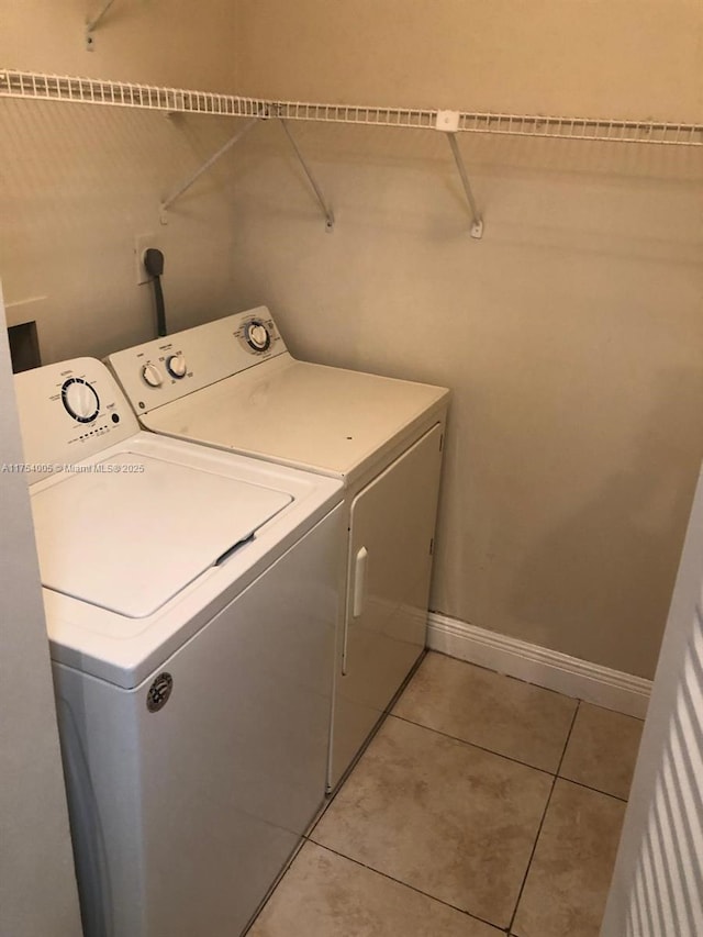 laundry room featuring laundry area, washing machine and dryer, baseboards, and light tile patterned flooring