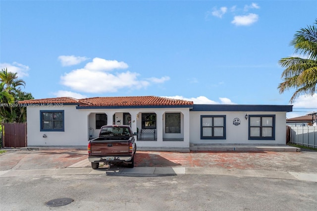 mediterranean / spanish house with a tile roof, fence, and stucco siding