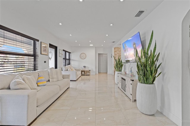 living room featuring marble finish floor, baseboards, arched walkways, and recessed lighting