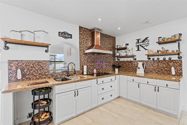 kitchen featuring open shelves, a sink, wall chimney range hood, light stone countertops, and black electric cooktop