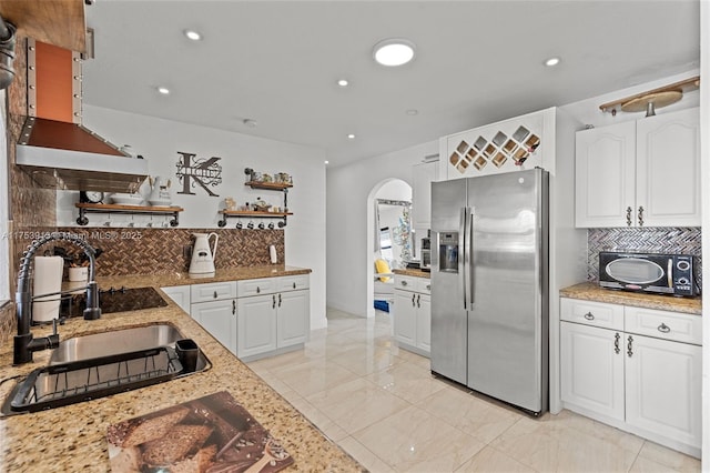 kitchen with arched walkways, open shelves, white cabinetry, a sink, and stainless steel fridge with ice dispenser