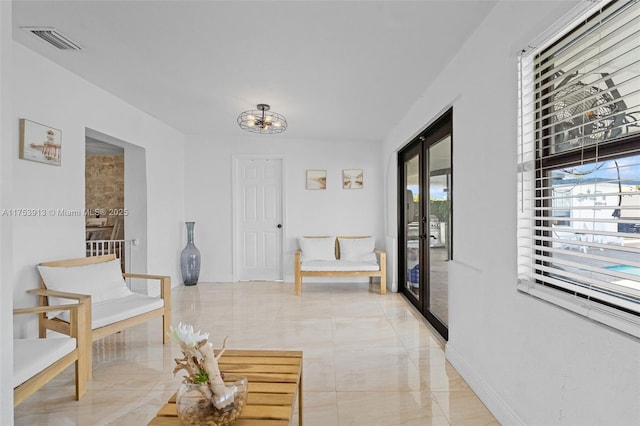 hallway with marble finish floor, visible vents, and baseboards