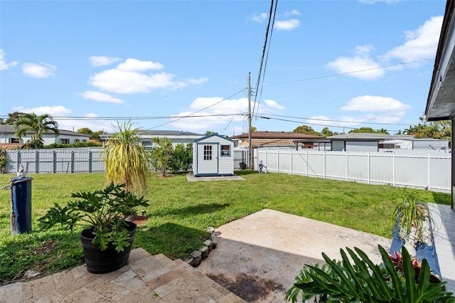 view of yard with an outbuilding, a patio, a storage unit, and a fenced backyard