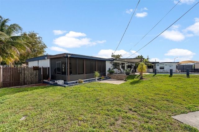 back of house featuring a yard, fence, and a sunroom