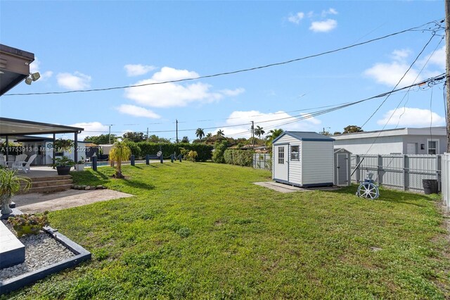 view of yard featuring an outbuilding, a patio area, fence, and a storage unit