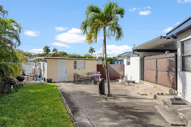 exterior space featuring an outbuilding, a patio area, fence, and a gate