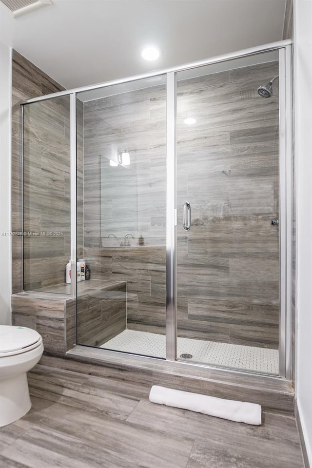 bathroom featuring toilet and a stall shower